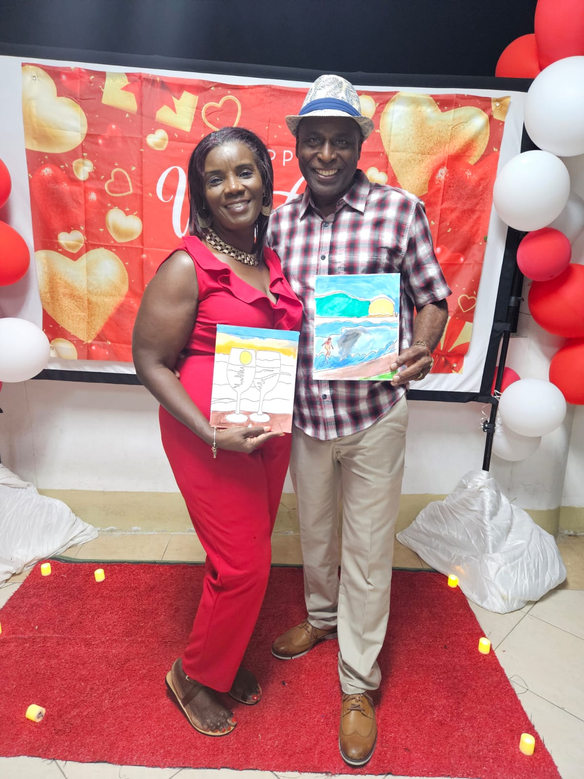 A smiling couple holding their paintings at the Marriage Ministry event