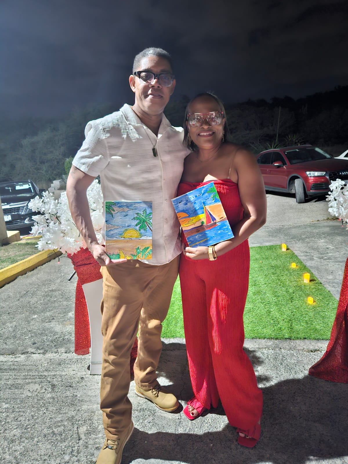 A couple holding their tropical and sailboat paintings