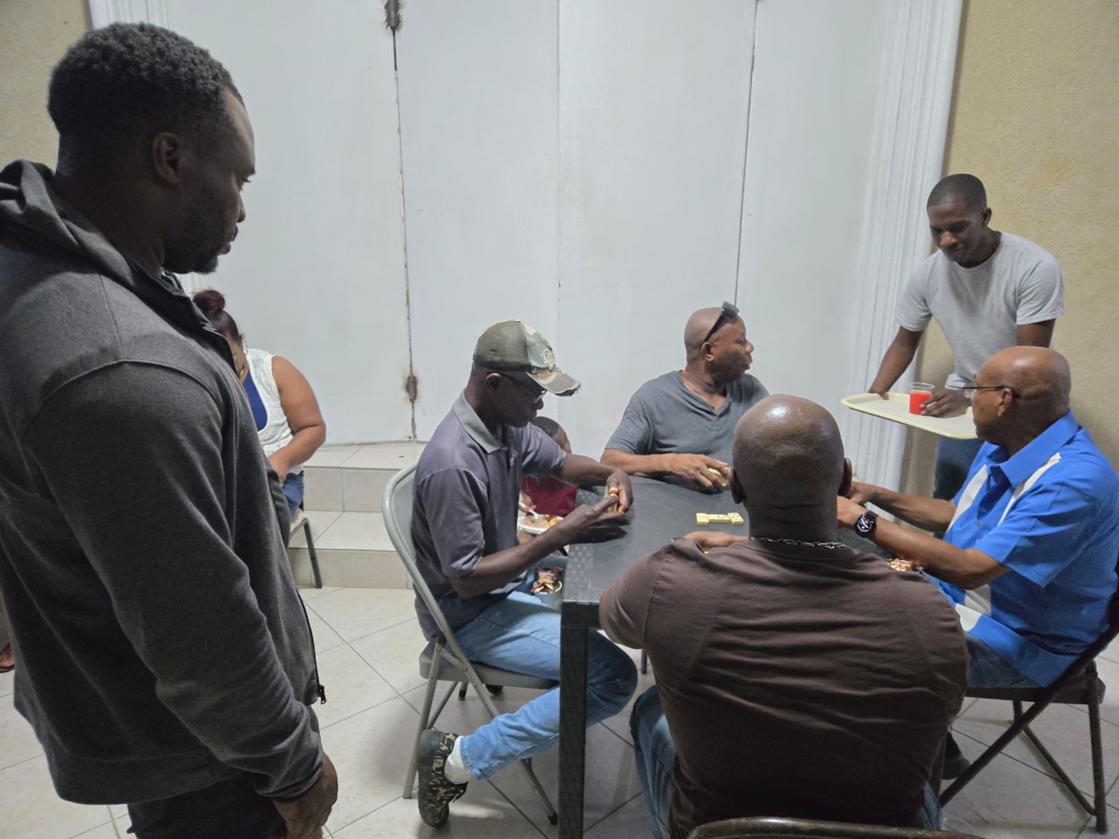 Men gathered around a table for dominoes and fellowship