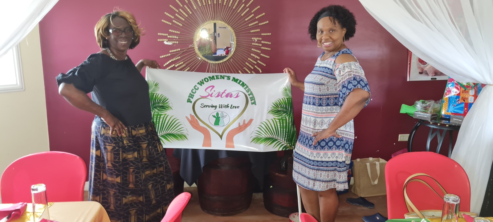 Women from PHCC holding the Women's Ministry Sistas banner